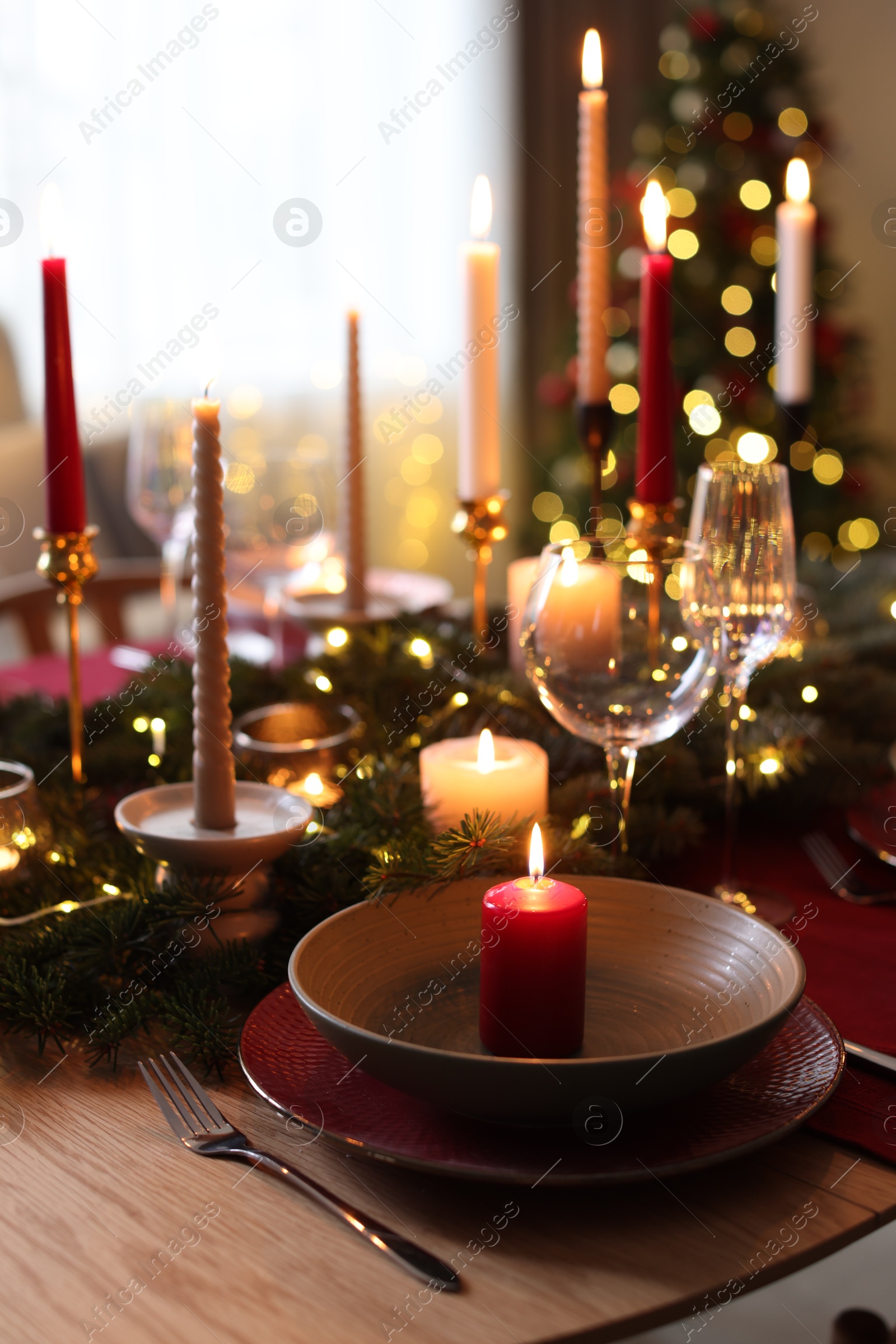 Photo of Festive table setting in room decorated for Christmas, closeup. Bokeh effect