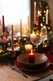 Photo of Festive table setting in room decorated for Christmas, closeup. Bokeh effect