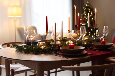 Photo of Festive table setting in room decorated for Christmas. Bokeh effect