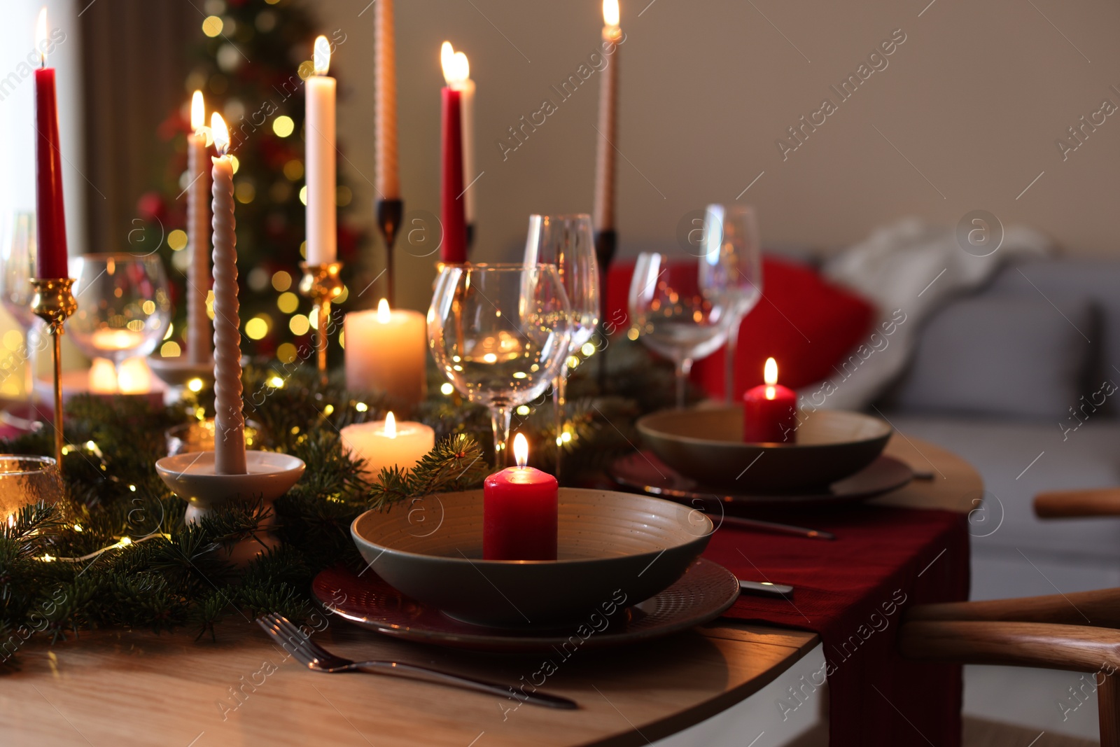 Photo of Festive table setting in room decorated for Christmas, closeup. Bokeh effect