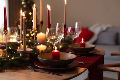 Photo of Festive table setting in room decorated for Christmas, closeup. Bokeh effect