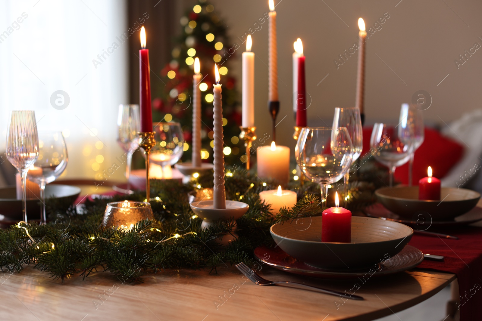 Photo of Festive table setting in room decorated for Christmas, closeup. Bokeh effect