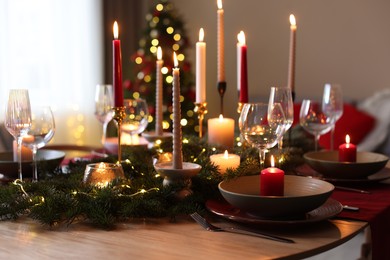 Photo of Festive table setting in room decorated for Christmas, closeup. Bokeh effect