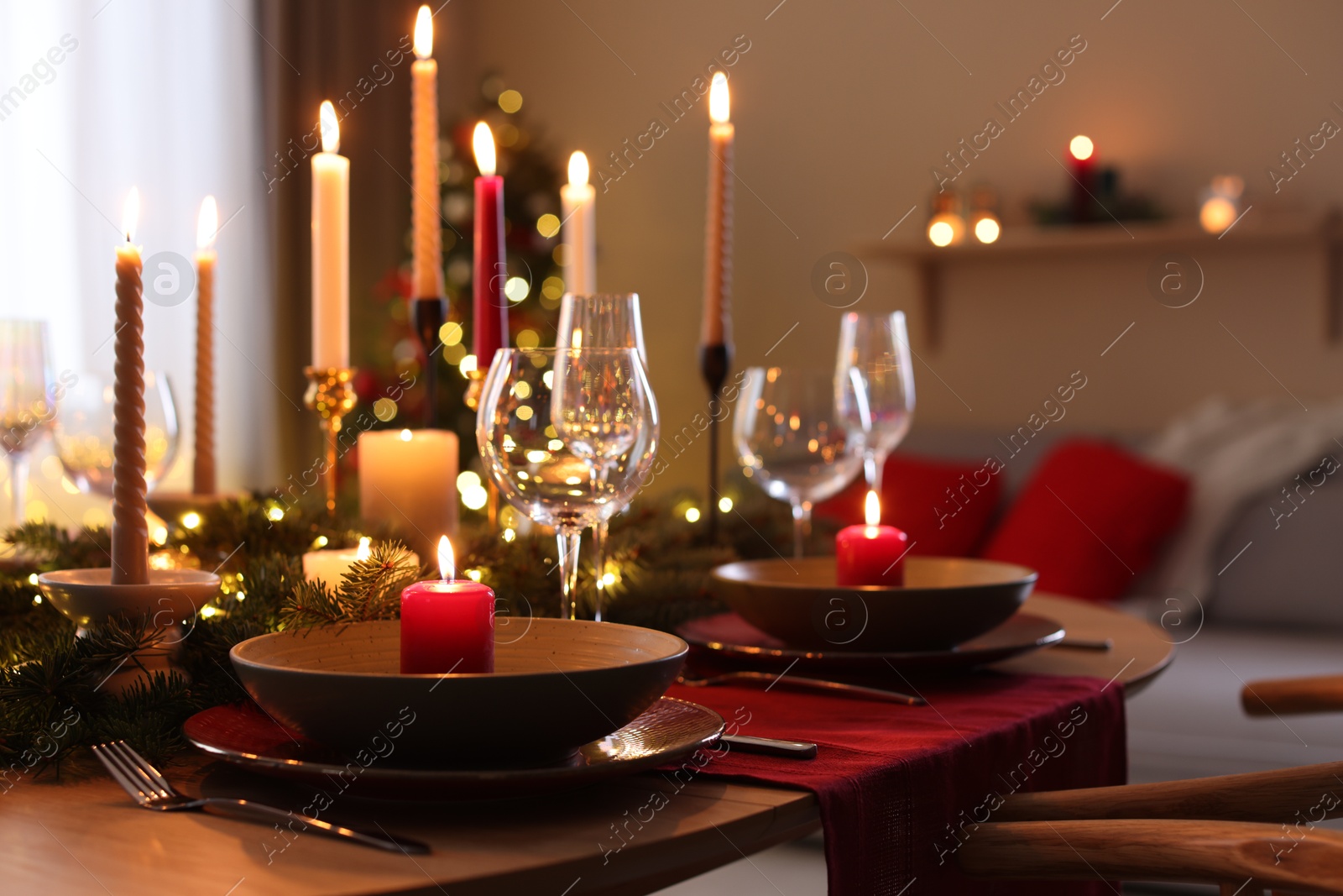 Photo of Festive table setting in room decorated for Christmas, closeup. Bokeh effect