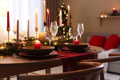 Photo of Festive table setting in room decorated for Christmas, closeup. Bokeh effect