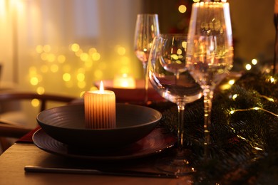 Photo of Festive table setting in room decorated for Christmas, closeup. Bokeh effect