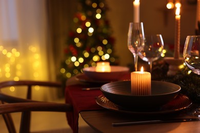 Photo of Festive table setting in room decorated for Christmas, closeup. Bokeh effect