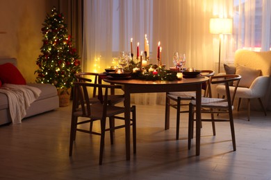 Photo of Festive table setting in room decorated for Christmas. Bokeh effect