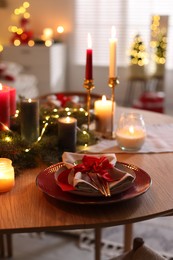 Photo of Festive table setting in room decorated for Christmas. Bokeh effect