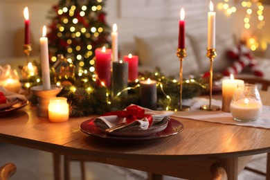 Photo of Festive table setting in room decorated for Christmas, closeup. Bokeh effect