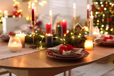 Photo of Festive table setting in room decorated for Christmas, closeup. Bokeh effect