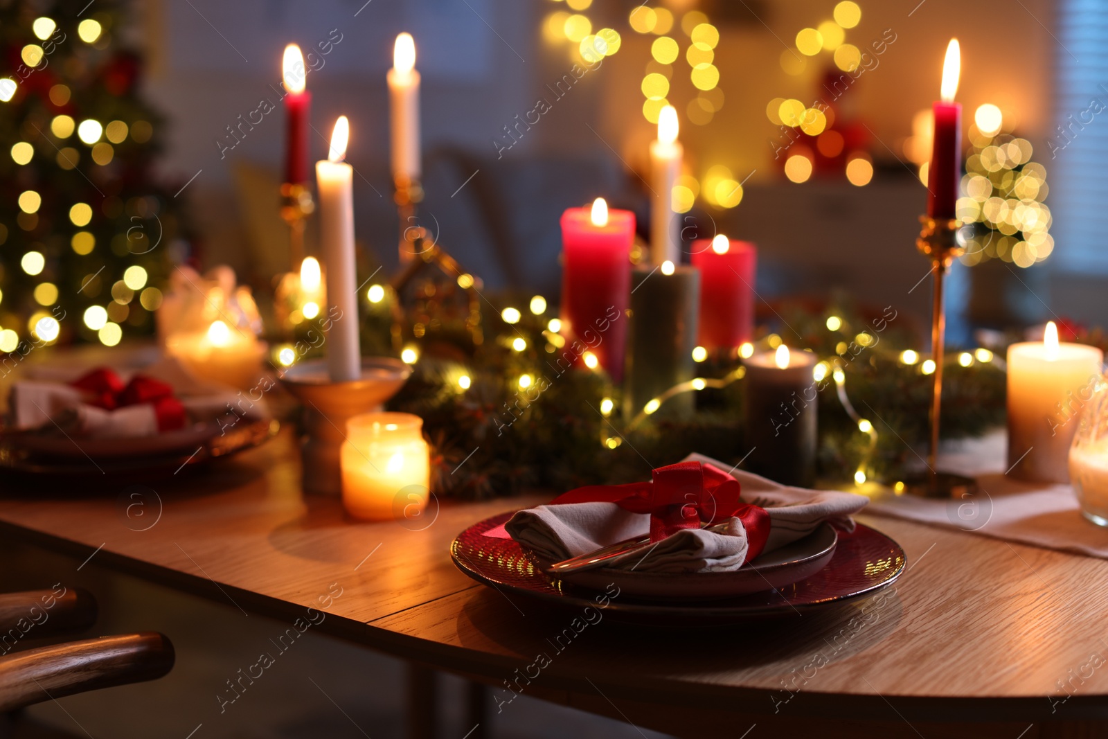 Photo of Festive table setting in room decorated for Christmas, closeup. Bokeh effect