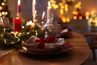 Photo of Festive table setting in room decorated for Christmas, closeup. Bokeh effect