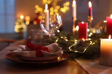 Photo of Festive table setting in room decorated for Christmas, closeup. Bokeh effect