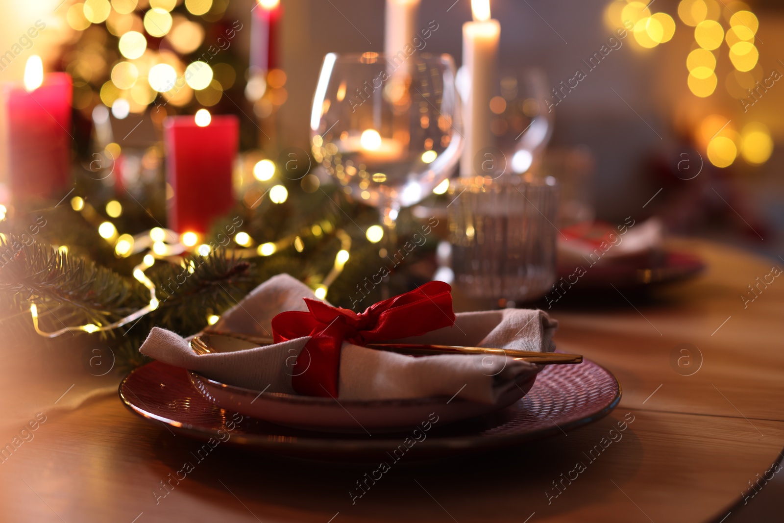 Photo of Festive table setting in room decorated for Christmas, closeup. Bokeh effect