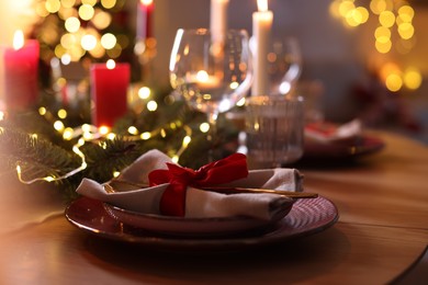 Photo of Festive table setting in room decorated for Christmas, closeup. Bokeh effect