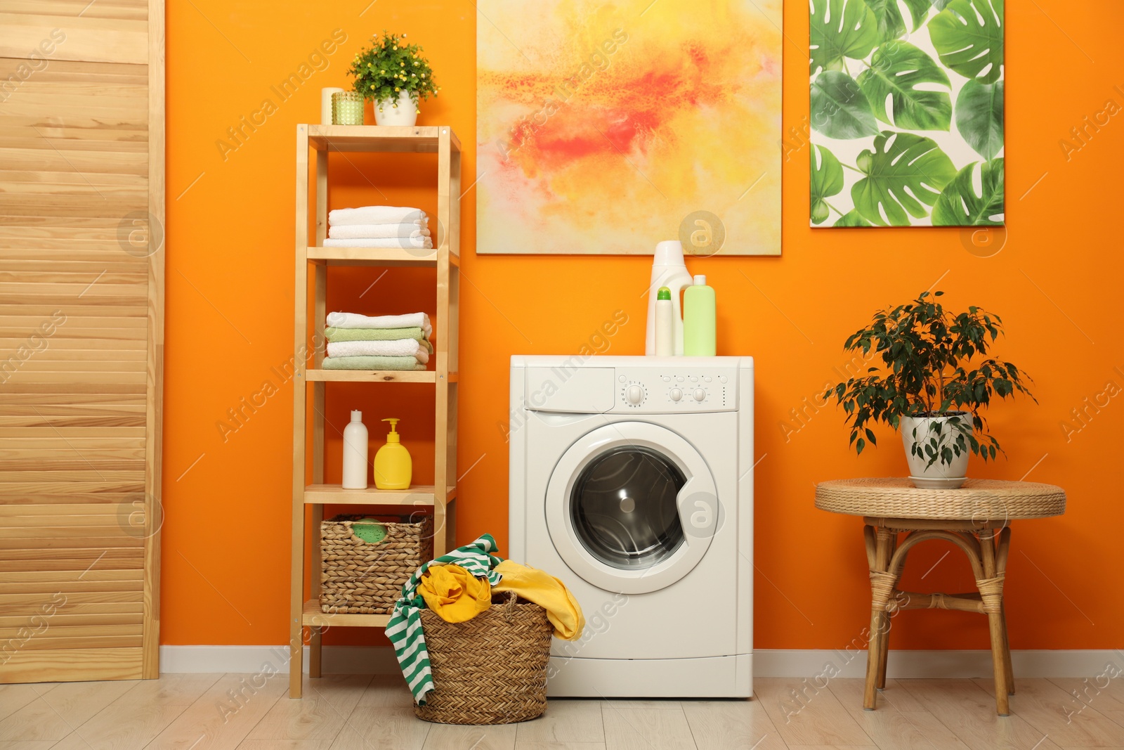 Photo of Washing machine, detergents and basket with laundry in room