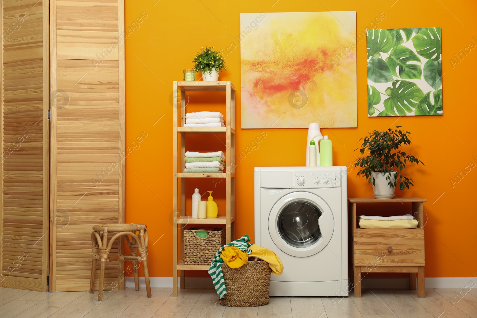 Photo of Washing machine, detergents and basket with laundry in room