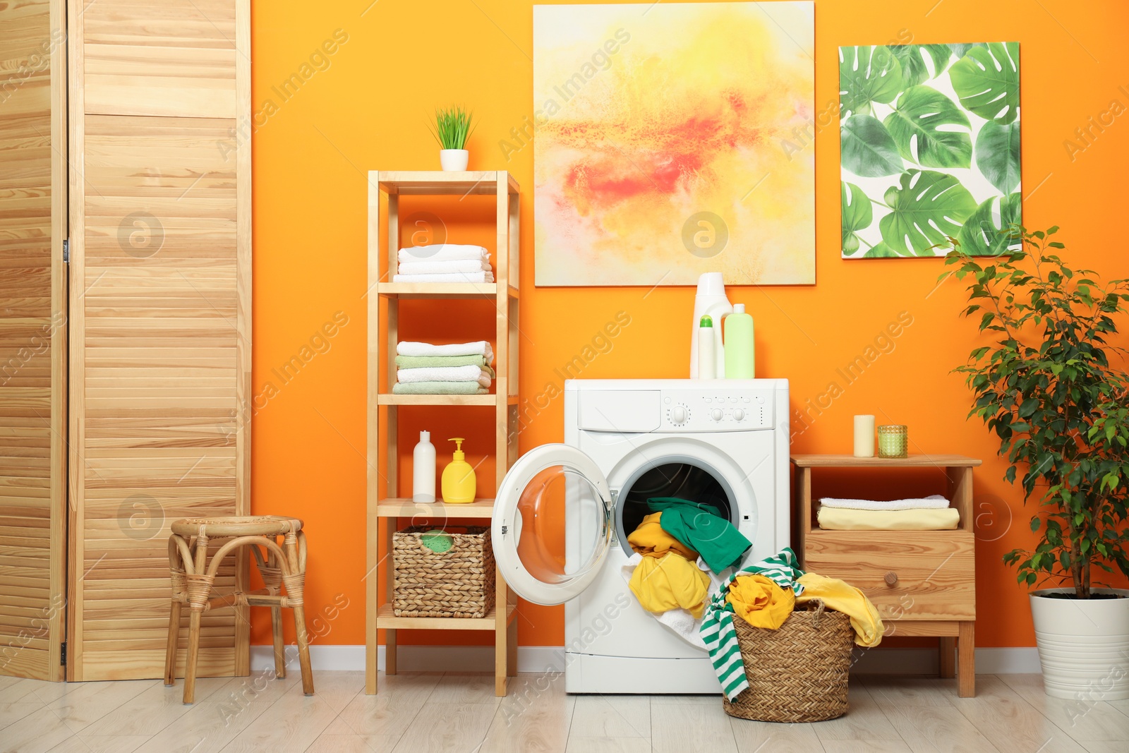 Photo of Washing machine, detergents and basket with laundry in room