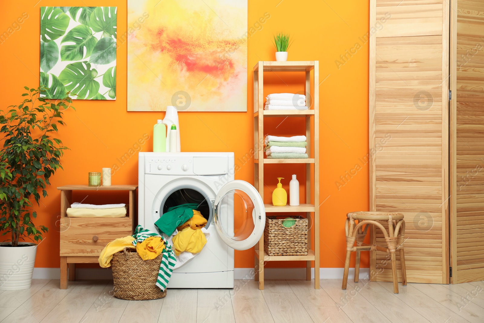 Photo of Washing machine, detergents and basket with laundry in room