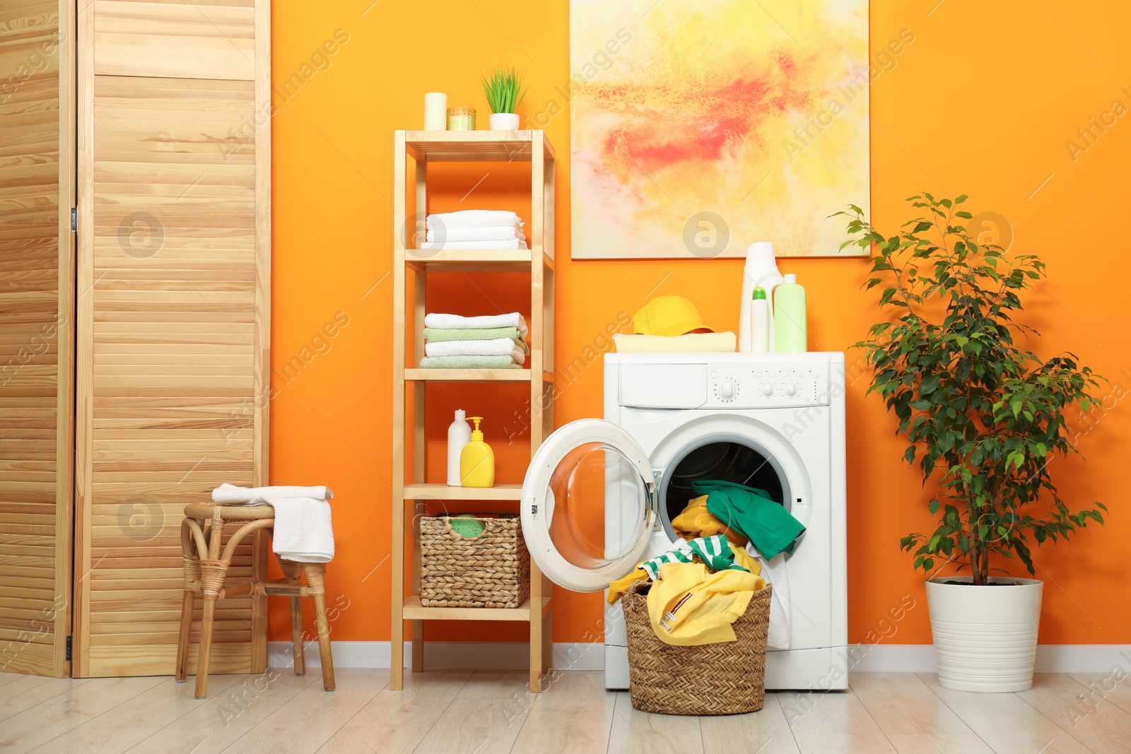 Photo of Washing machine, detergents and basket with laundry in room