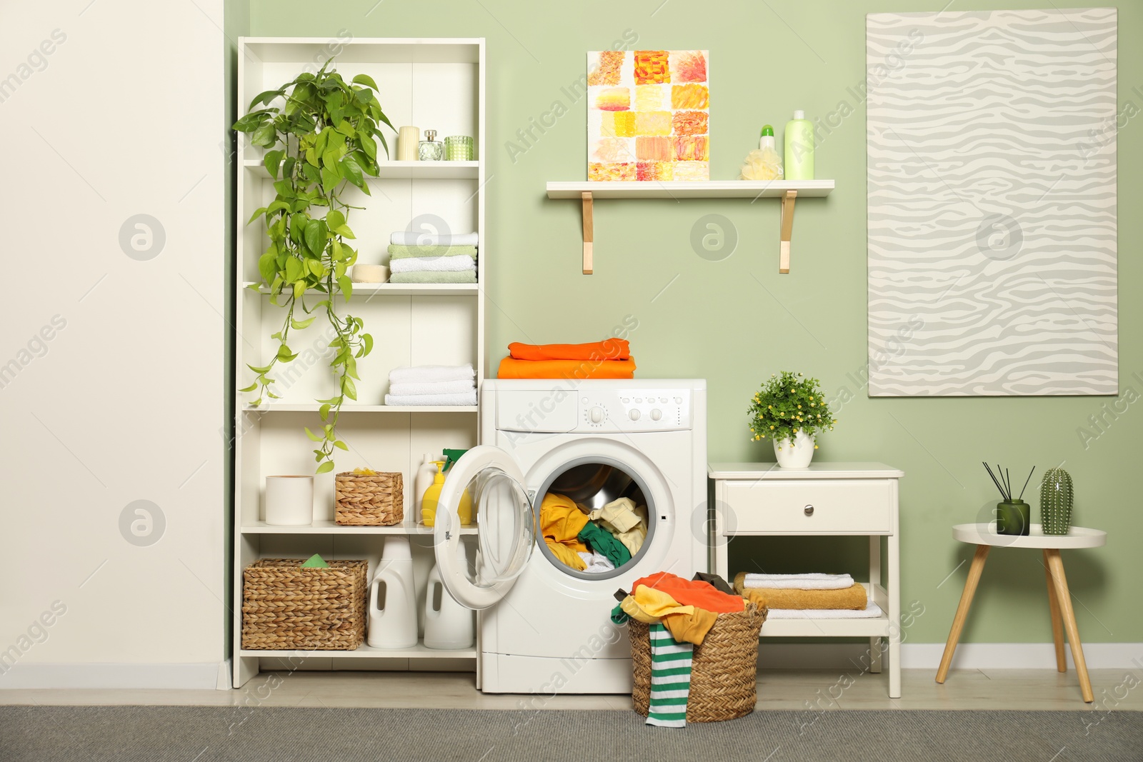 Photo of Washing machine, detergents and basket with laundry in room