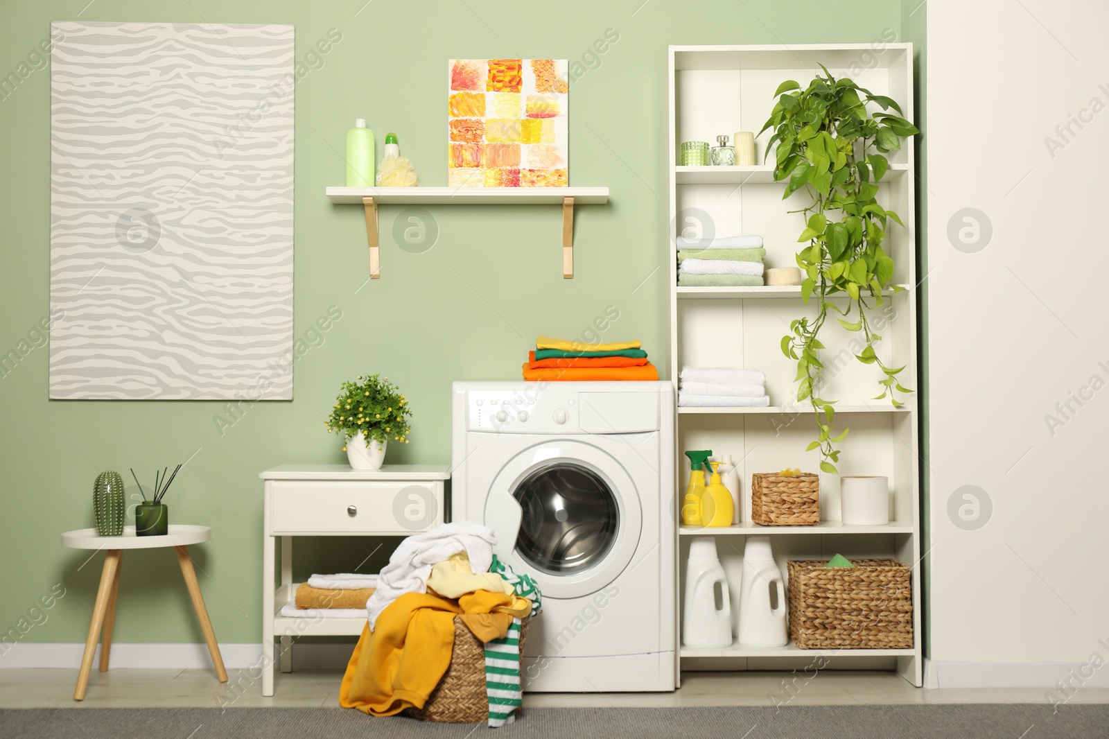 Photo of Washing machine, detergents and basket with laundry in room