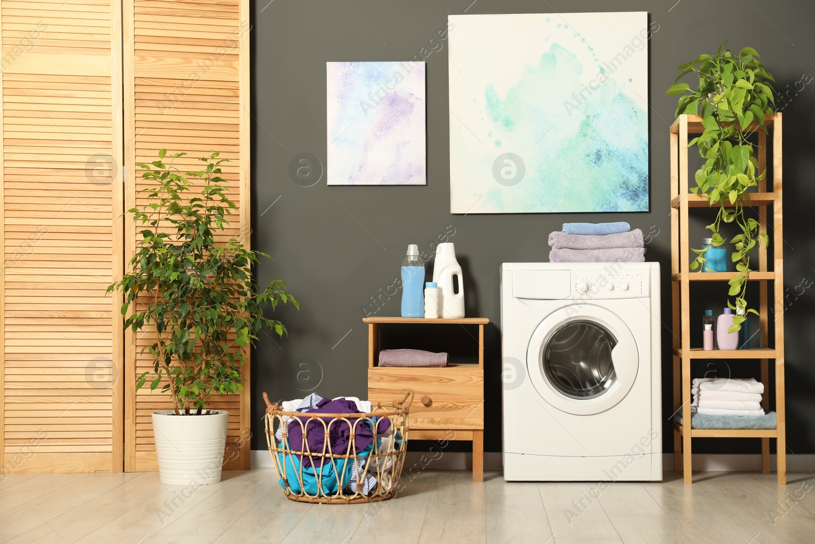 Photo of Washing machine, detergents and basket with laundry in room