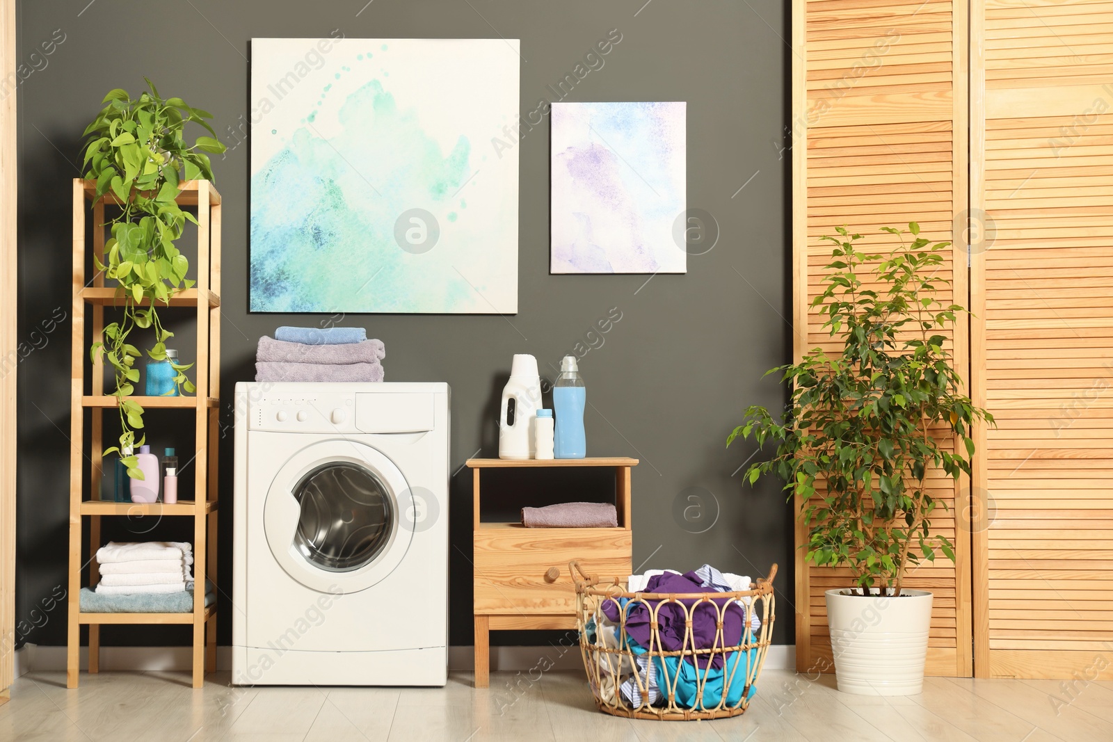 Photo of Washing machine, detergents and basket with laundry in room