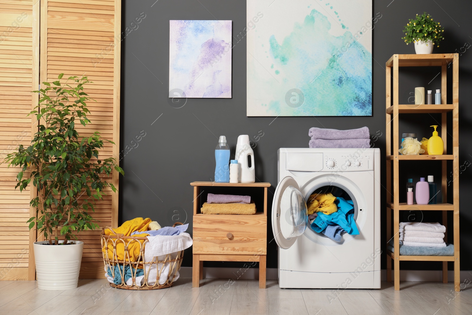 Photo of Washing machine, detergents and basket with laundry in room