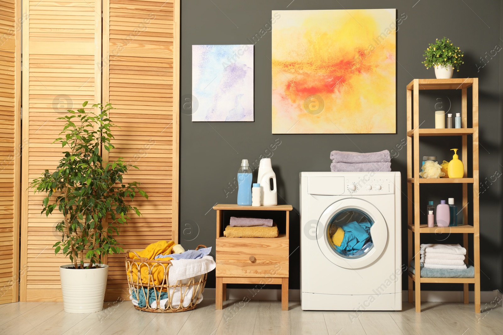 Photo of Washing machine, detergents and basket with laundry in room