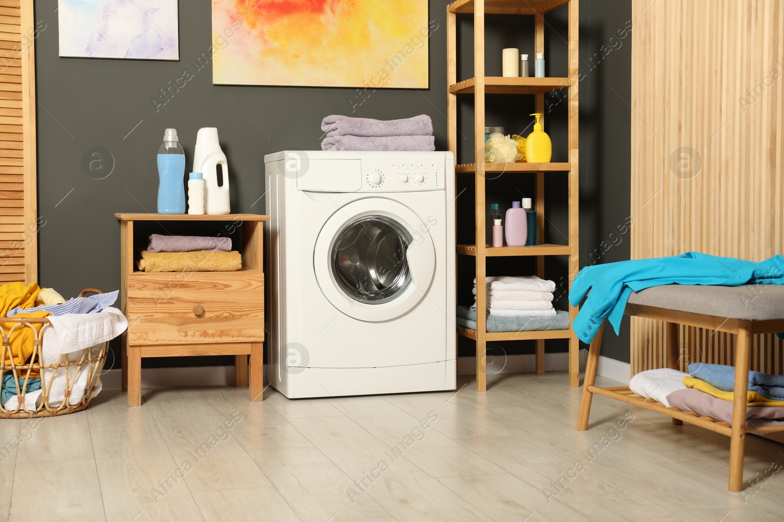 Photo of Washing machine, detergents and basket with laundry in room