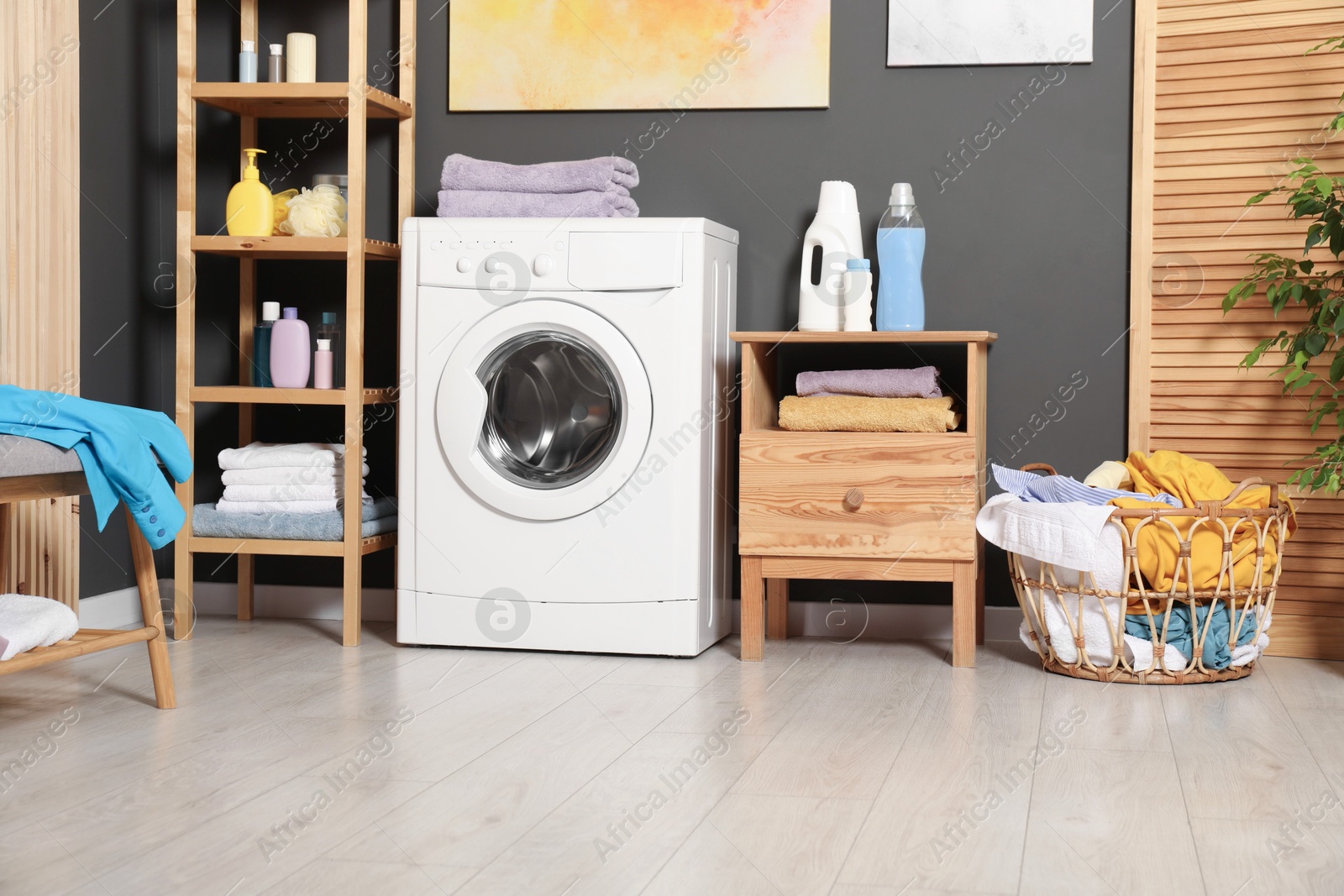 Photo of Washing machine, detergents and basket with laundry in room