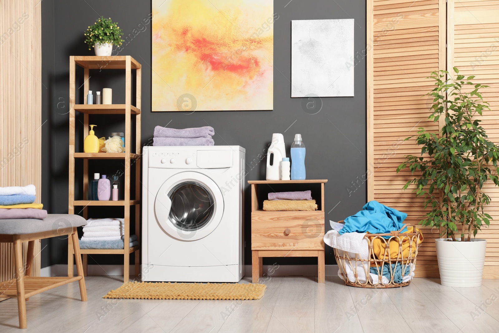 Photo of Washing machine, detergents and basket with laundry in room