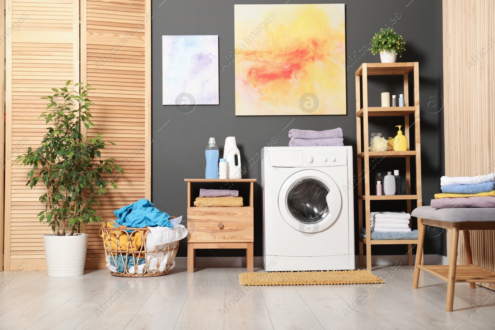 Photo of Washing machine, detergents and basket with laundry in room