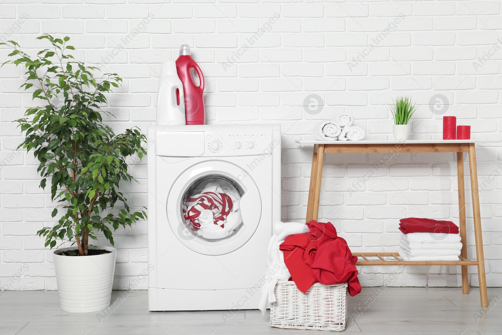 Photo of Washing machine, detergents and basket with laundry in room