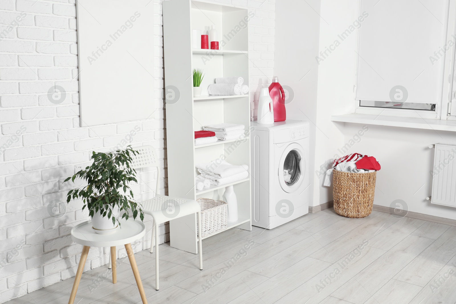 Photo of Washing machine, detergents and basket with laundry in room