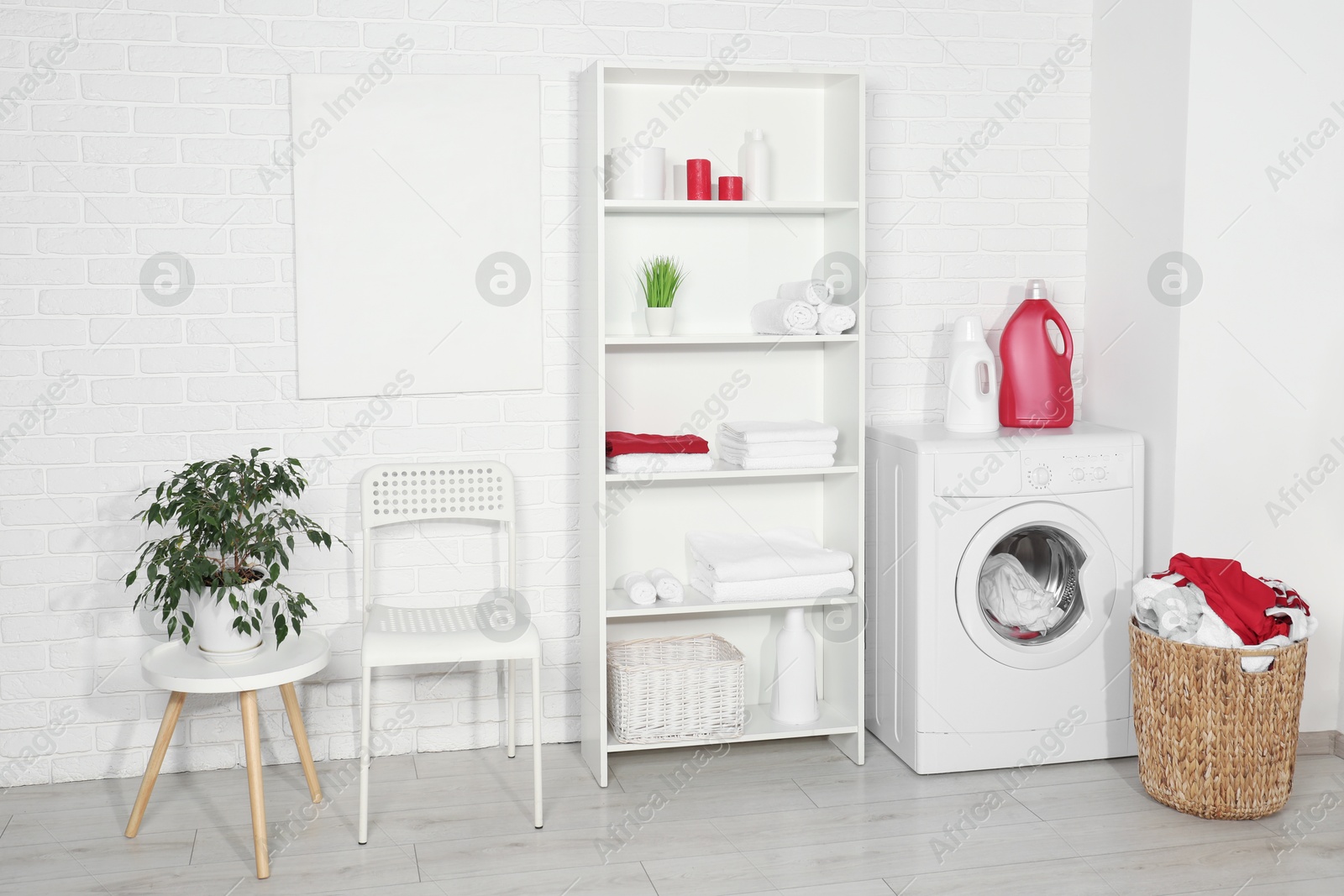 Photo of Washing machine, detergents and basket with laundry in room