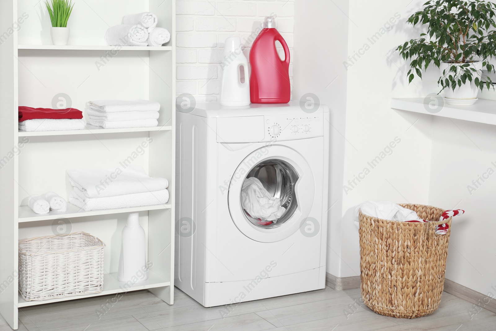 Photo of Washing machine, detergents and basket with laundry in room