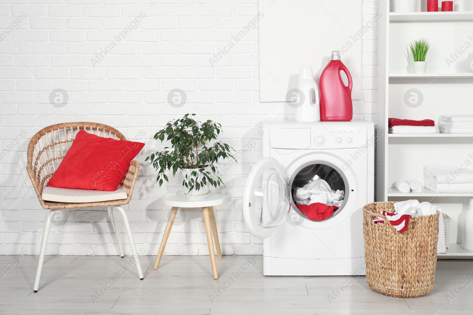 Photo of Washing machine, detergents and basket with laundry in room