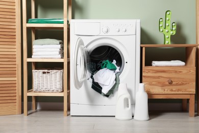 Photo of Washing machine, detergents and towels in room