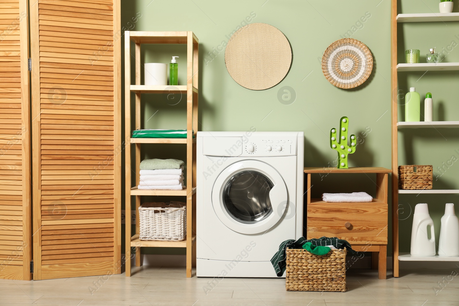 Photo of Washing machine, detergents and basket with laundry in room