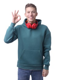 Photo of Happy young man with headphones showing OK gesture on white background