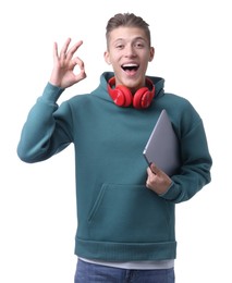 Photo of Young man with headphones and laptop showing OK gesture on white background