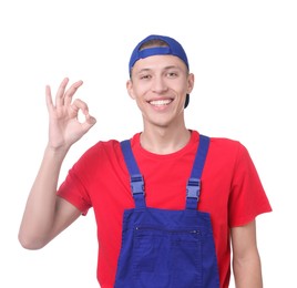 Happy young man in uniform showing OK gesture on white background