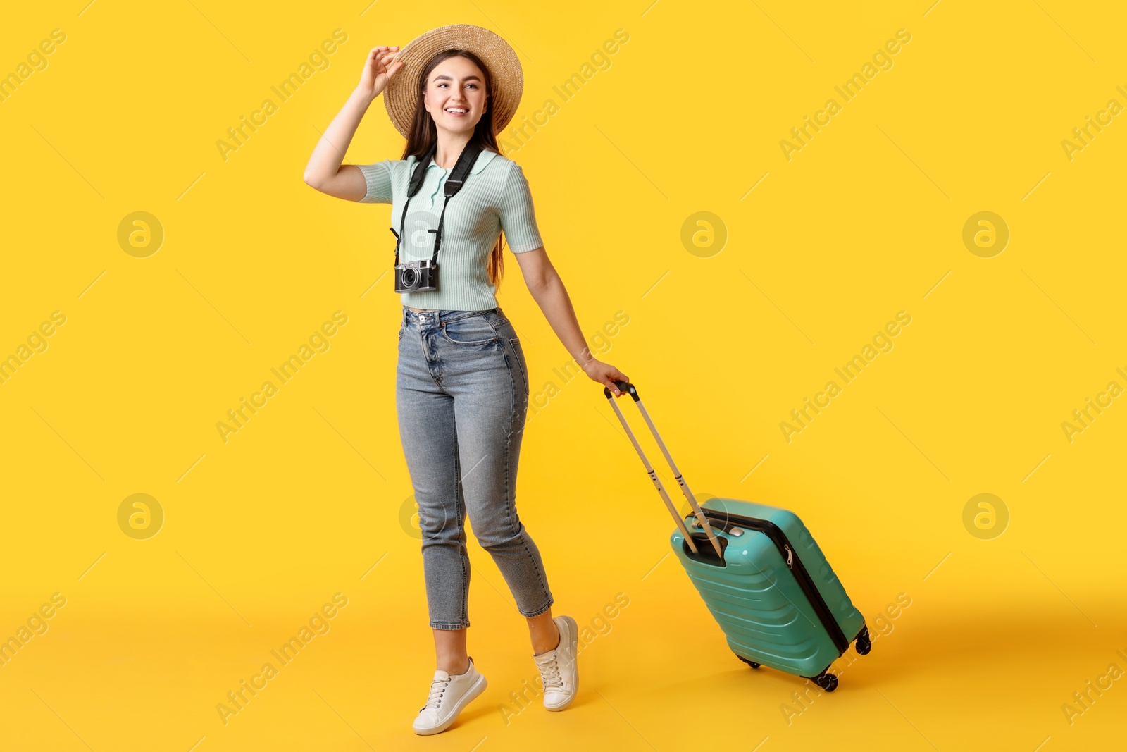 Photo of Happy woman with vintage camera and suitcase on orange background