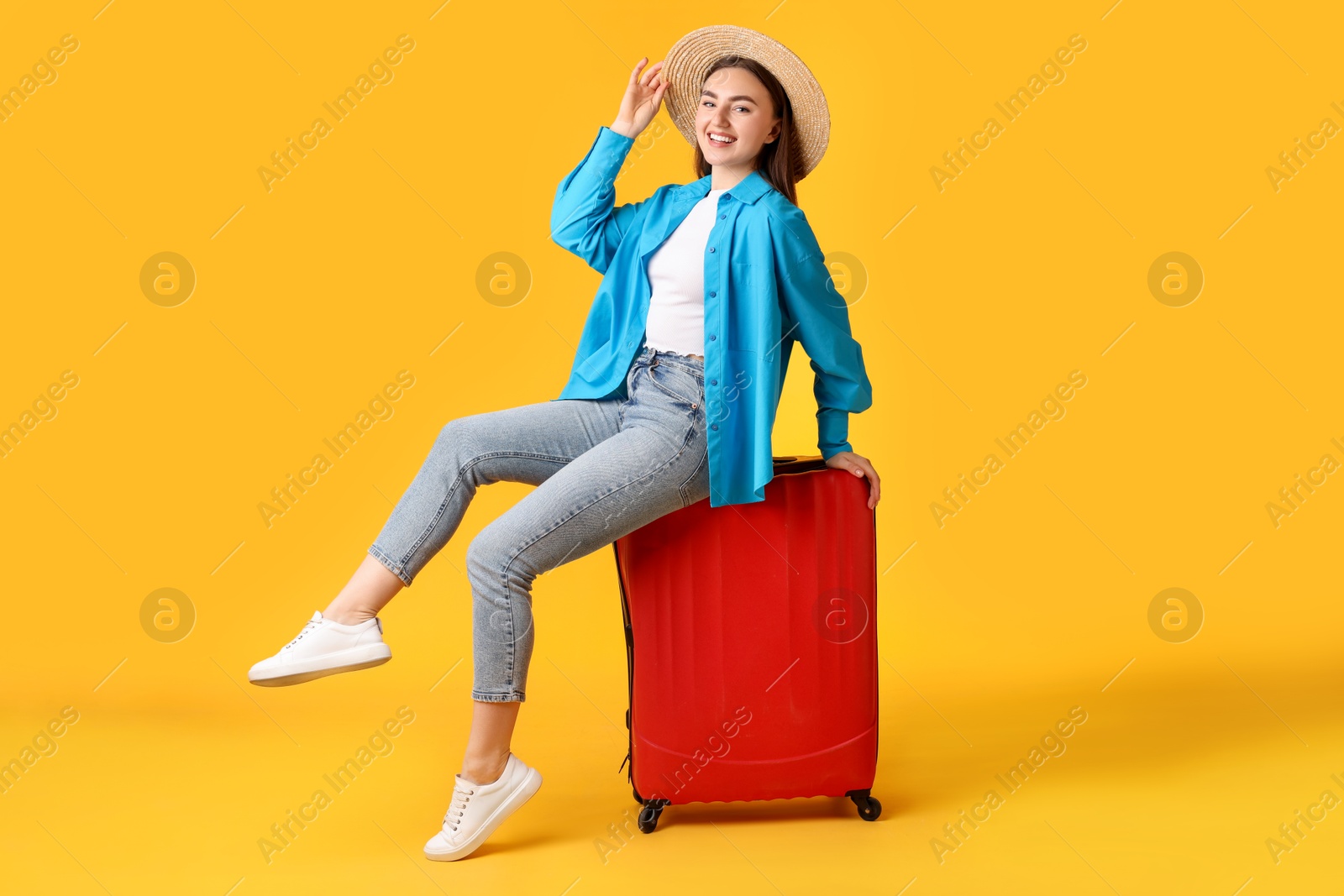 Photo of Woman in straw hat with suitcase on orange background