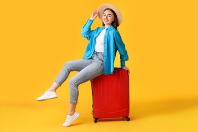 Photo of Woman in straw hat with suitcase on orange background