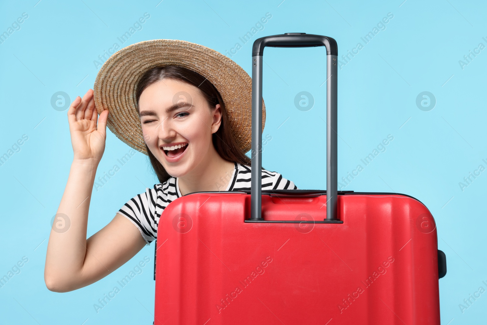 Photo of Woman in straw hat with suitcase on light blue background