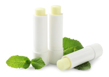 Photo of Mint lip balms and green leaves isolated on white. Cosmetic product